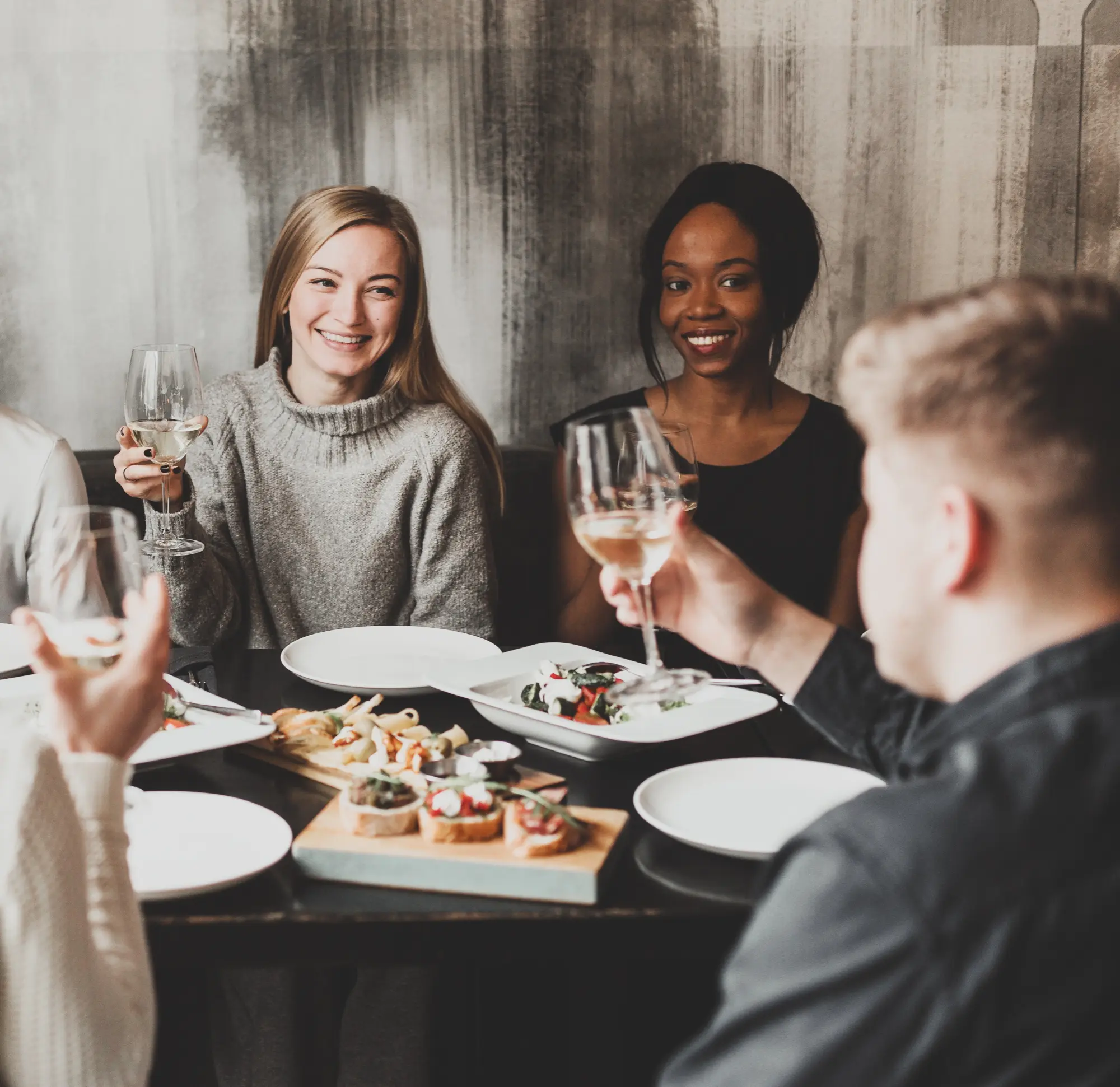 Freunde stoßen bei einem privaten Steaks-&-Wine-Event mit Weißwein an